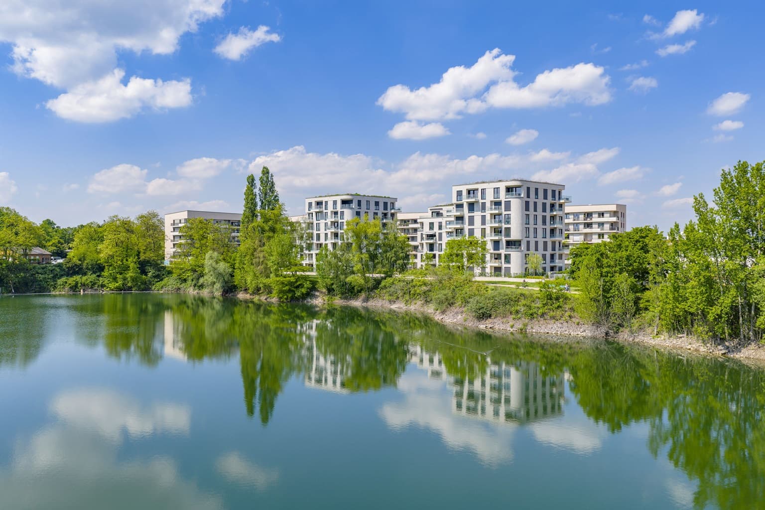 Blick auf das Wohnquartier PANDION Albertussee in Düsseldorf mit modernen Mehrfamilienhäusern am See.