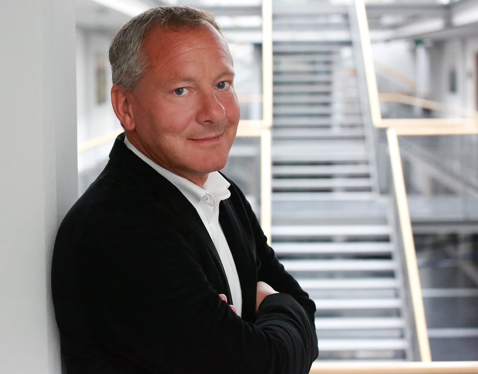 Alexander Pommer, Expansionsmanager von FitX, im Porträt vor einer modernen Treppenhauskulisse.
