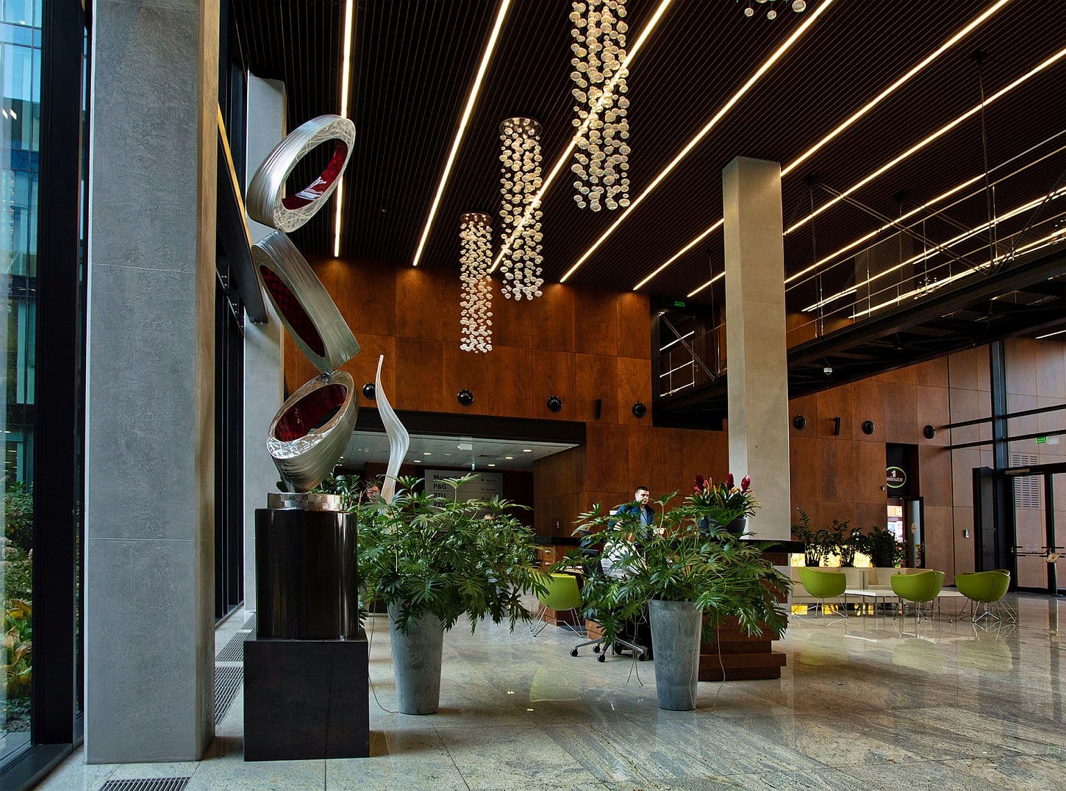 Innenansicht des modernen Lobbys des Konstruktorska Business Center in Warschau mit Rezeption und Kunstskulptur.