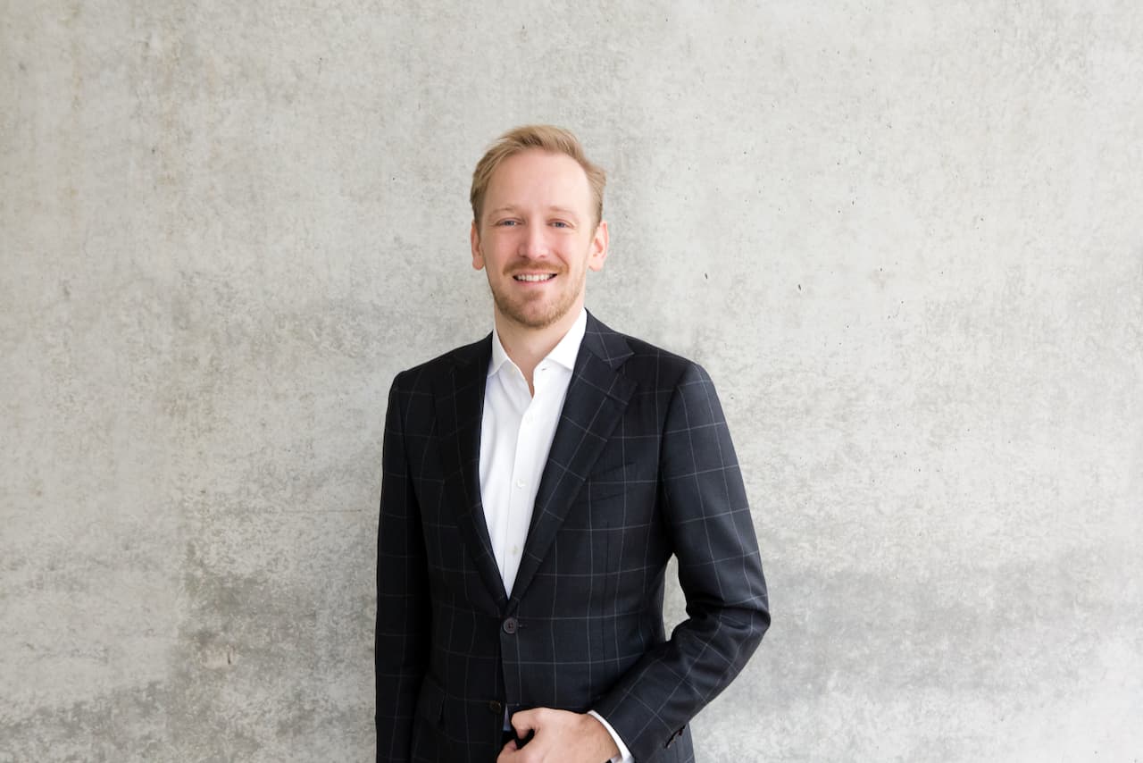 Portrait von Christian Behnke, Geschäftsführer der sh+ GmbH, vor einer grauen Wand.