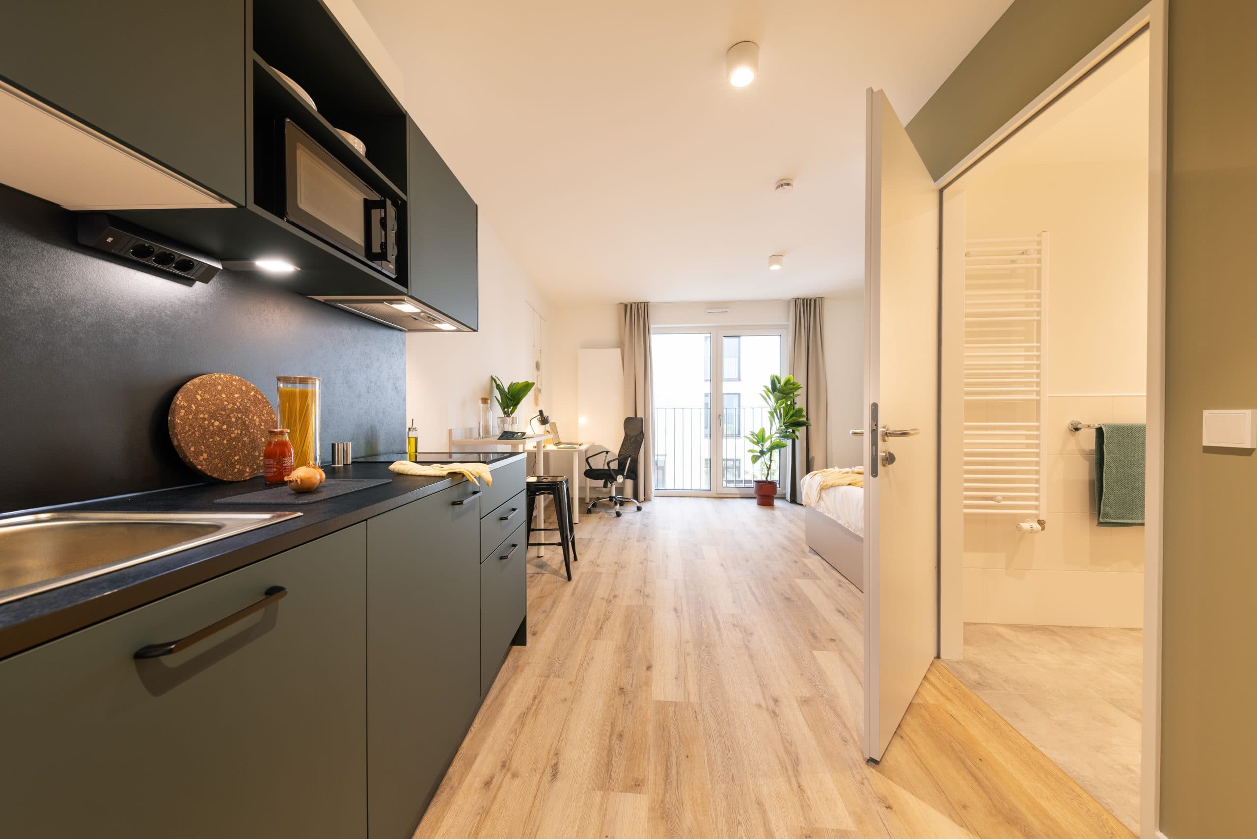 Blick in ein voll möbliertes Studio-Apartment mit Küche, Arbeitsplatz und Bad im THE FIZZ Berlin Friedrichshain.