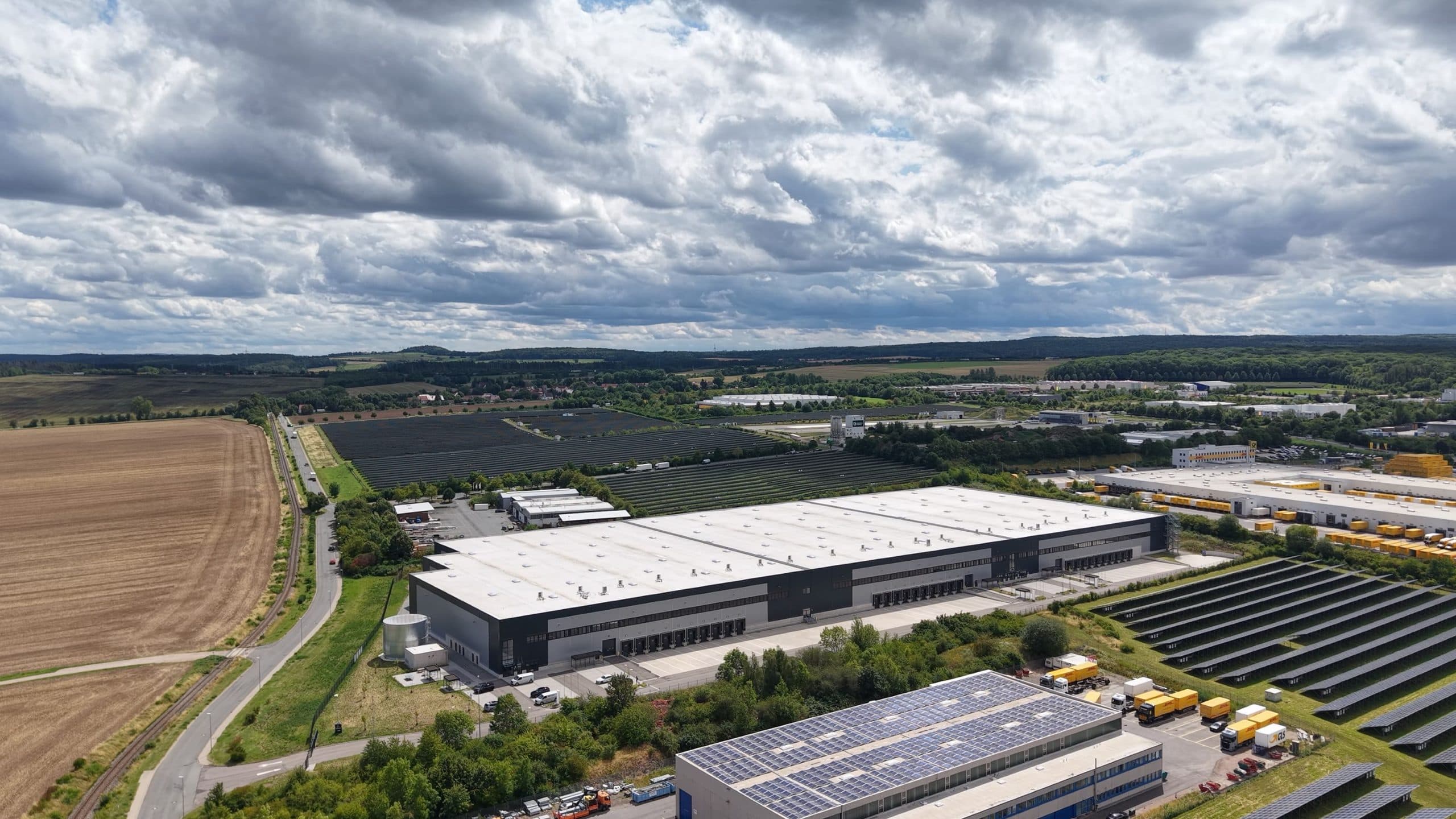 Außenansicht des FOCUS Logistikparks in Nohra mit umliegenden Feldern und Solaranlagen.