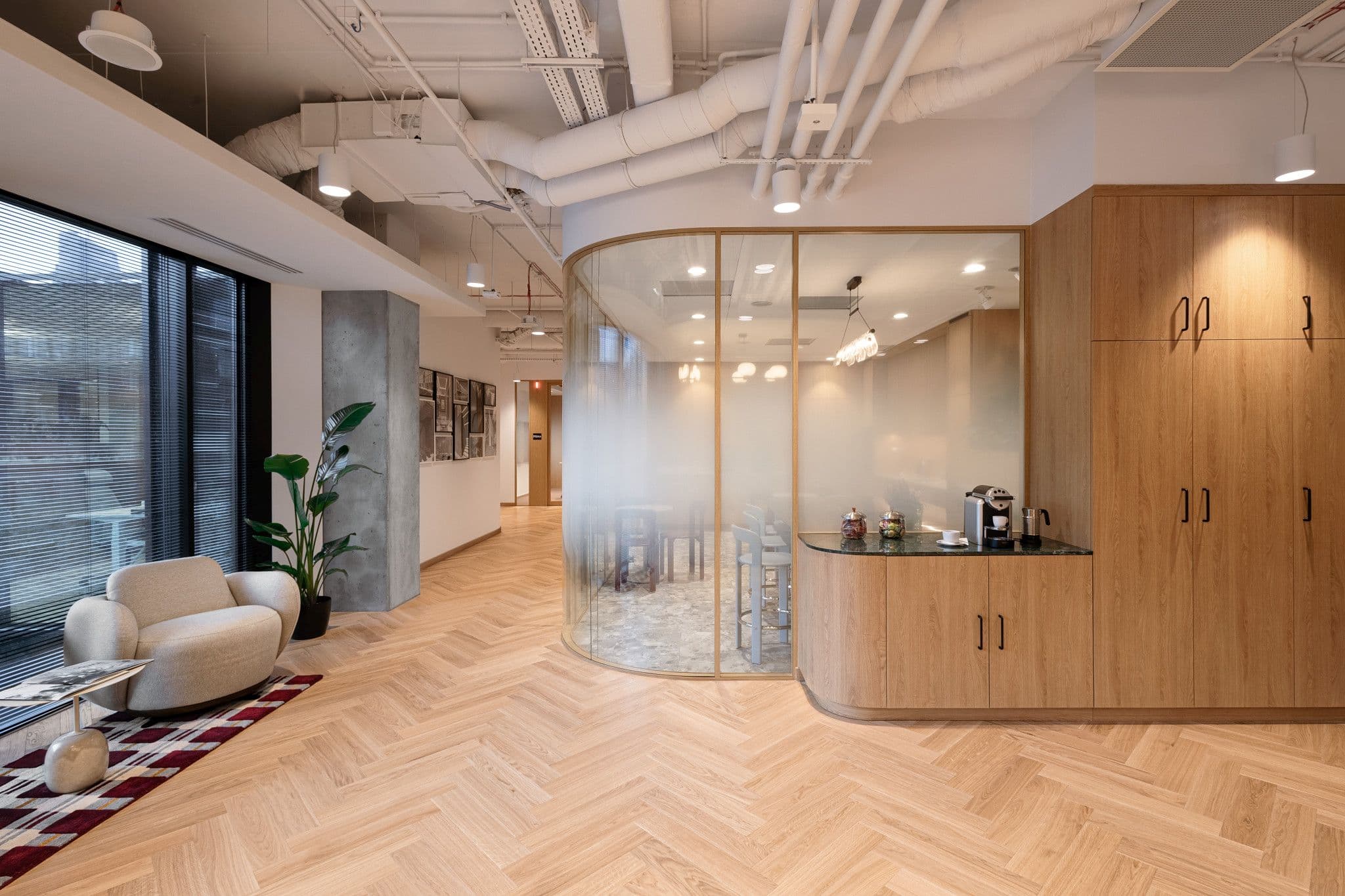 Lounge-Bereich mit Sessel, Teppich und moderner Küche im Yareal-Büro in LIXA C, Warschau