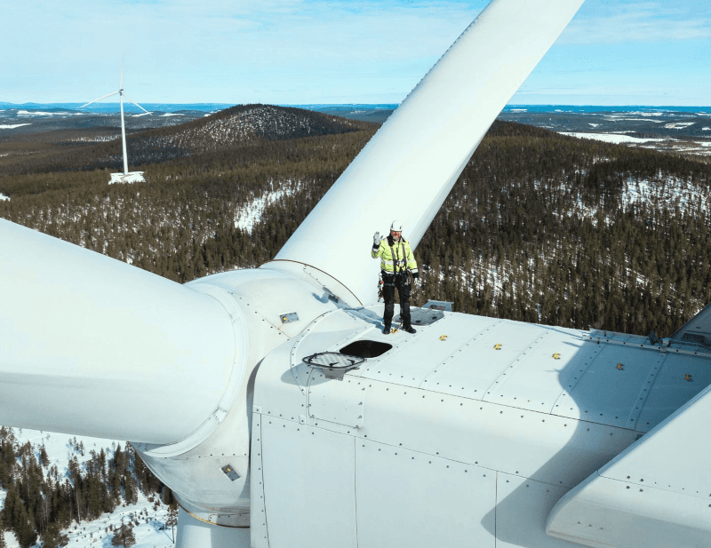 Techniker arbeitet auf einer Windkraftanlage zur Wartung im Winterwald