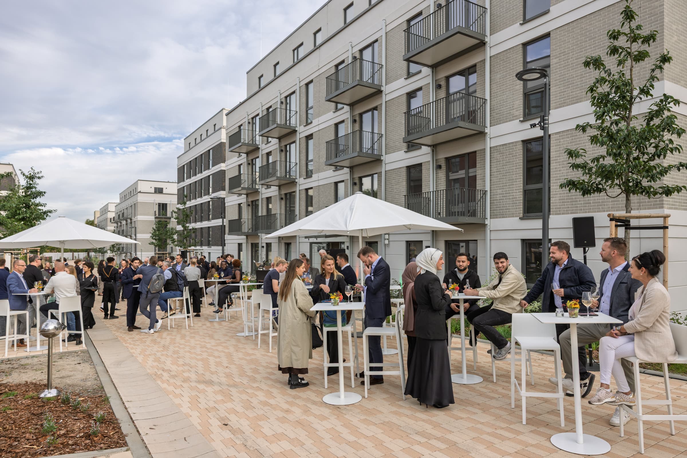Gäste bei der Eröffnungsfeier von Momento Berlin in Berlin-Neukölln auf dem Außengelände des neuen Wohnquartiers