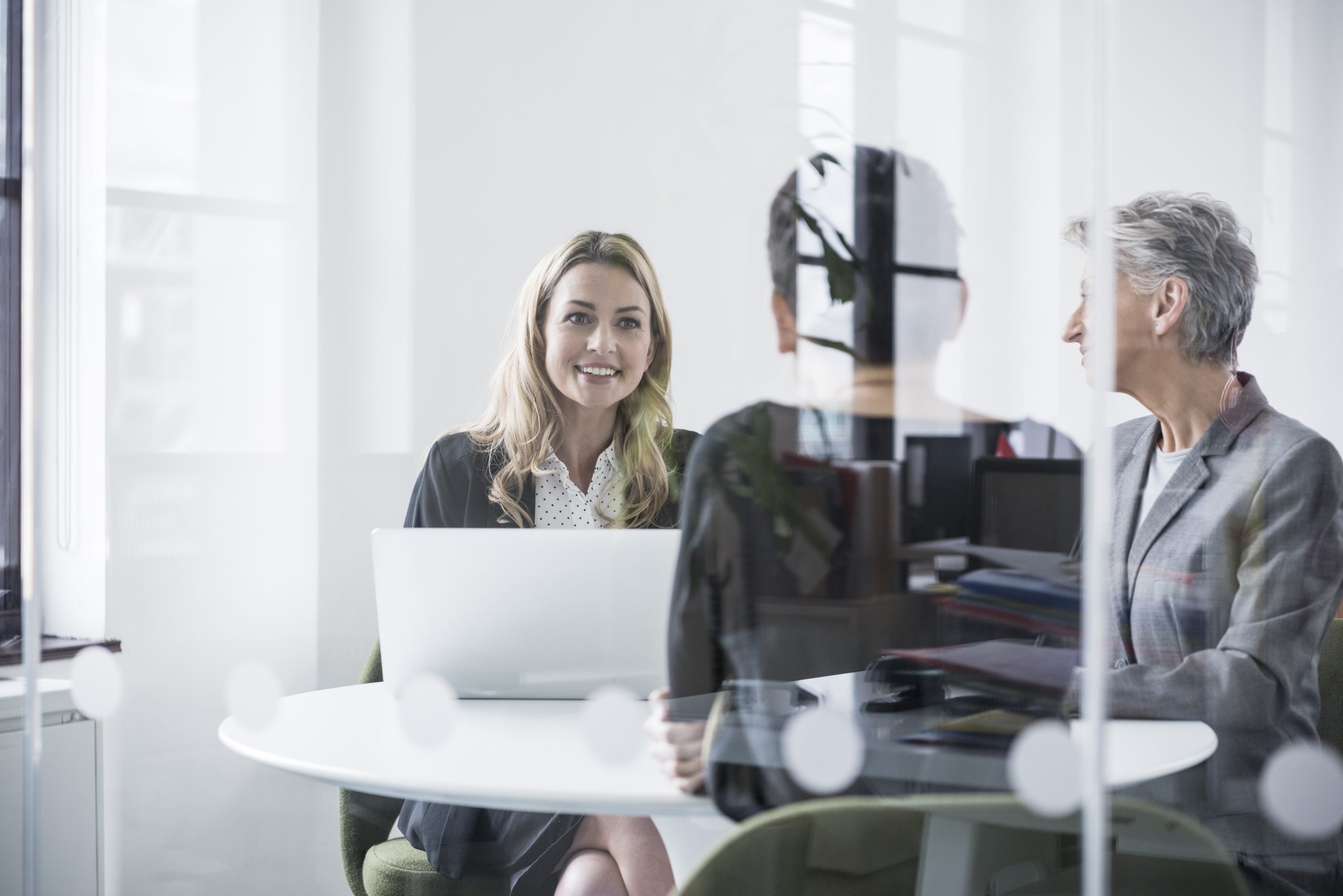 Female colleagues behind glass screen in meeting room