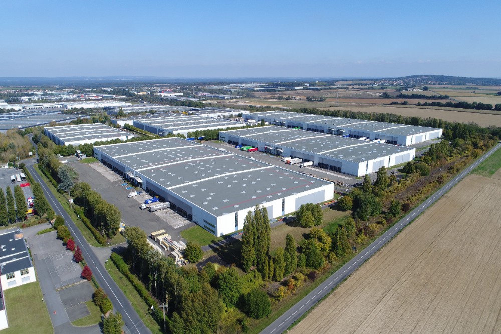 Luftaufnahme des SEGRO Logistics Park in Marly-la-Ville mit mehreren Logistikhallen im Grünen.