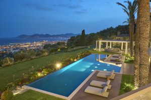 Luxuriöse Villa mit Pool und moderner Terrasse und Blick auf Cannes und das Meer bei Abenddämmerung.