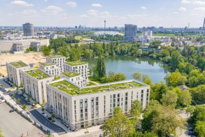 Luftaufnahme des Wohnquartiers PANDION Albertussee am See in Düsseldorf mit modernen Mehrfamilienhäusern und begrünten Dächern.
