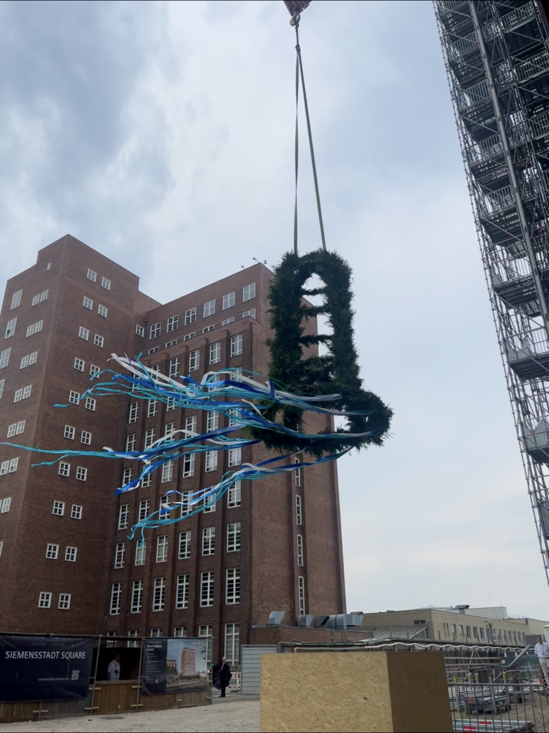 Richtkranz schwebt vor dem Atriumgebäude von Siemensstadt Square in Berlin beim Richtfest.