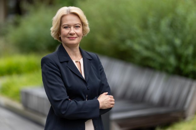 Daiva Rakauskaitė, Partnerin von Aneli Capital, steht im Freien vor einer Bank.