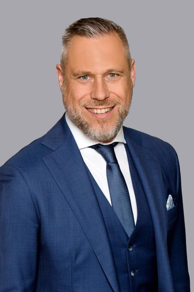 Porträt von Michael R. Baumann im blauen Anzug, Head of Capital Markets Germany bei Colliers.