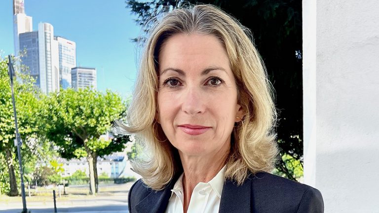 Marion Knief, Head of Marketing bei Newmark, im Freien vor urbanem Hintergrund