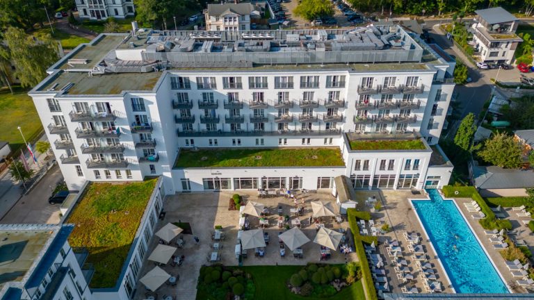 Luftbild des Steigenberger Grandhotel mit Außenpool und Terrasse, Gäste sitzen unter Sonnenschirmen.