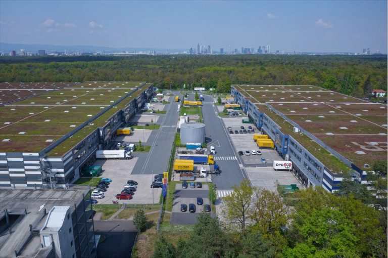 Luftaufnahme des Logistikobjekts „An der Gehespitz" in Neu-Isenburg mit mehreren Lagerhallen und Logistikfahrzeugen.