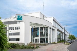 Moderne Bürogebäude der Dr. Peters Group in Dortmund mit DS-Logo und Fahnen vor dem Eingang.