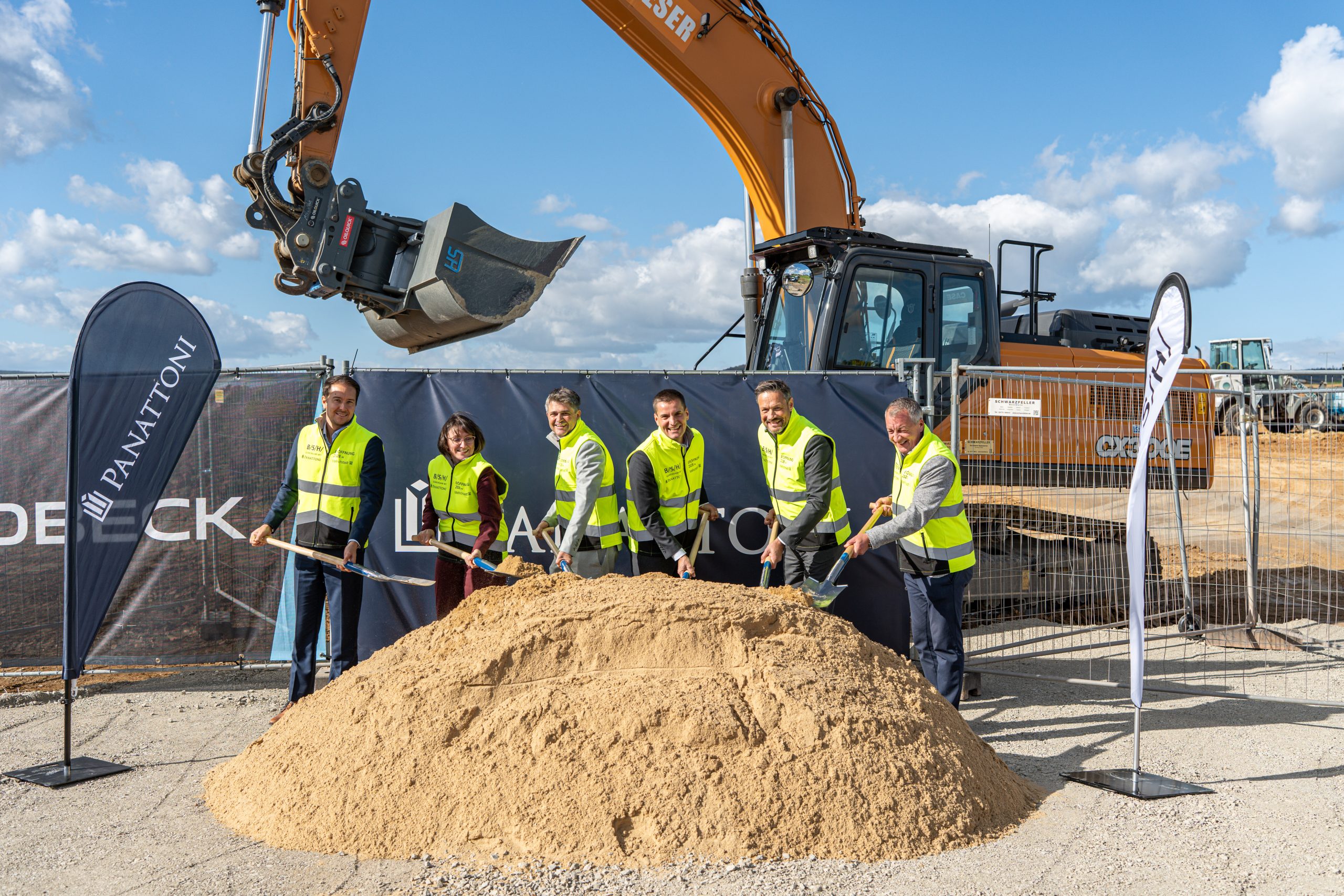 Gruppenbild am symbolischen Spatenstich für den neuen Produktions- und Logistikstandort der BSH Hausgeräte GmbH mit Beteiligten vor einem Bagger.