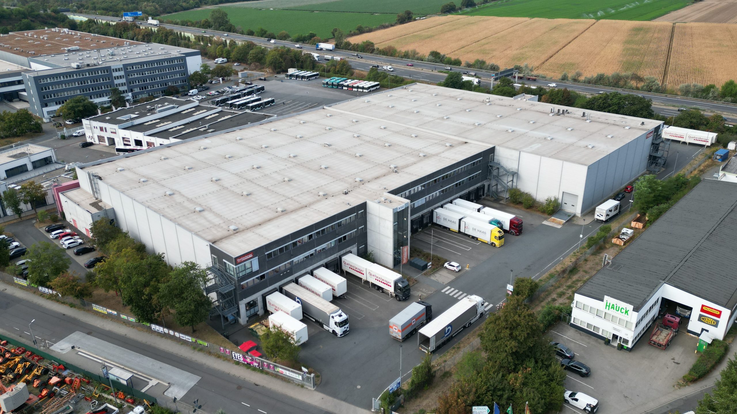 Luftaufnahme einer Logistikimmobilie in Weiterstadt, vermietet an De Haas Road Cargo, mit mehreren Lkw und Hallenflächen.